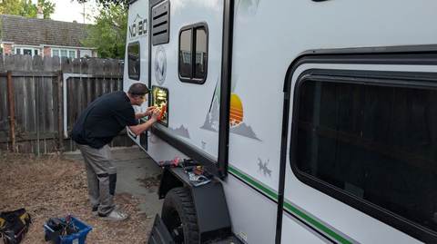Technician repairing RV electrical system at customer location